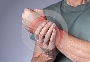 Man suffering from wrist pain and holding painful hand with red spot closeup. Hand injury. Health care, medicine concept