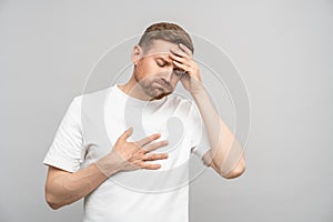 Man suffers from heartburn, nausea and pain in head. Guy holds head, chest with exhausted expression