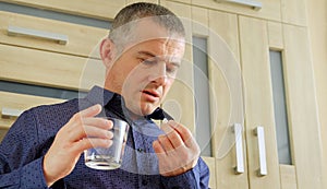 A man suffers from migraines. Going to take a headache pill. Holds a glass of water. Migraine