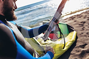 Man sufrers in wetsuits with kite equipment for surfing