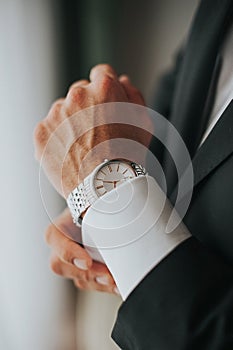 Man in a suit adjusts his watch on the wirst