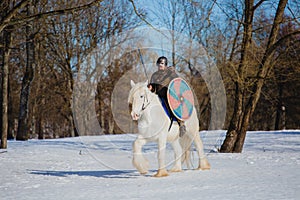 Man in suit of ancient viking riding big white horse