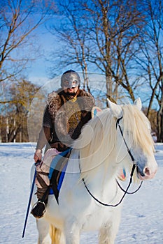 Man in suit of ancient warrior riding big white horse