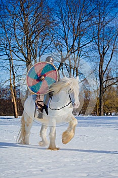 Man in suit of ancient warrior riding big white horse