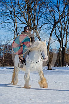 Man in suit of ancient warrior riding big white horse