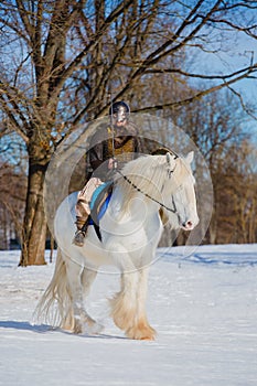 Man in suit of ancient warrior riding big white horse