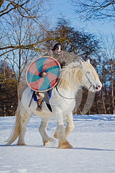 Man in suit of ancient warrior riding big white horse