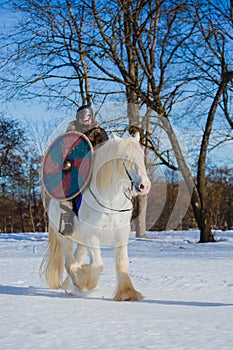 Man in suit of ancient warrior riding big white horse