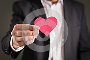 Man in a suit and a cardboard paper heart.