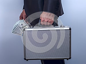 Man in suit carries metal briefcase with dollars