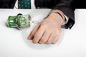 Man in suit chained with handcuffs to money