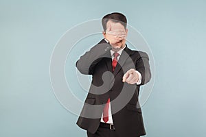 Man in suit closed eyes and pointing finger at camera