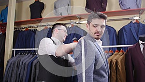 Man suit concept. Seller helps the buyer choose a suit in the clothing store