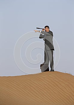 Man in a suit in a desert with a spyglass