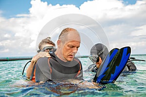 A man in a suit for diving prepares a boy to dive