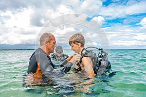 A man in a suit for diving prepares a boy to dive