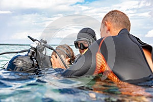 A man in a suit for diving prepares a boy to dive