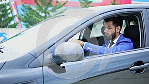 Man in suit driving the car. Muslim man with serious face driving left-hand car.