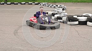 Man in suit driving Go-Kart car in racing track.