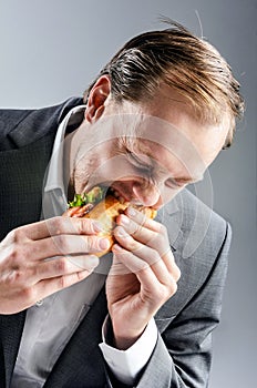 Man in suit eats BLT eagerly photo