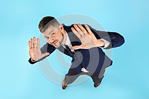 Man in suit evading something on light blue background, above view