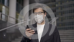 A man in a suit and face mask to protect himself from new dreadful viruses browsing the Internet using smartphone in