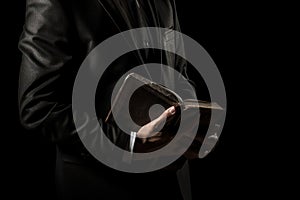 Man in suit holding a bible in his arm on a black background. AI generated