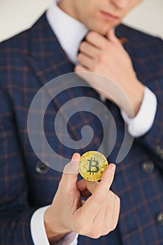 Man in suit holding a golden bitcoin - symbol of international virtual cryptocurrency. Isolated on white.