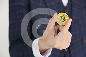 Man in suit holding a golden bitcoin - symbol of international virtual cryptocurrency. on white.