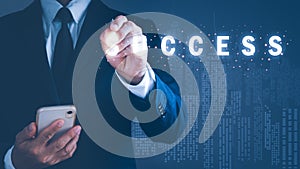 a man in a suit holding a mobile phone Left hand holding a pen pointing to the word success, background blur. The concept is