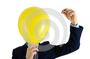 Man in suit holding needle over yellow air balloon, a moment before bubble burst. Isolated on white.