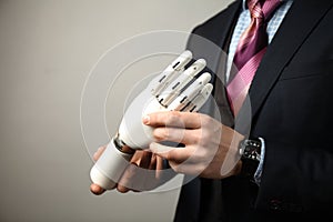 Man in suit holding prosthesis artificial man`s hands