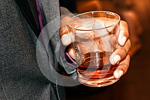 man in a suit holding whiskey at a party in high society