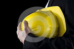 Man in a suit holding a yellow hardhat