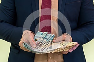 A man in a suit holds a large pile of Ukrainian money and shows his income.  new banknotes 1000 and 500 hryvnia