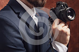 Man in suit holds old camera