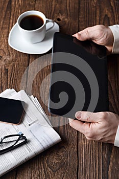 A man in a suit holds a tablet, a cup of coffee is standing nearby. Work outside the office, distance learning. Business Ideas.