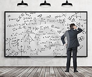 Man in suit looking at whiteboard with formulas