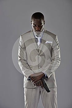 Man in a suit looks down as he holds his gun