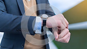 A man in a suit looks at the time at his wristwatch.