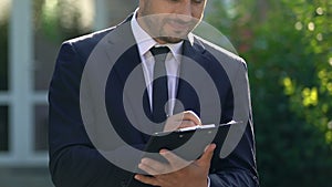Man suit making notes, real estate agent filling contract details smiling camera