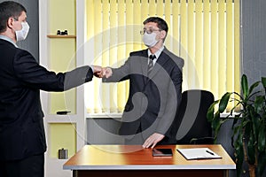 Man in a suit and medical face mask got up from the table to gre