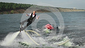 A man in a suit performs tricks on a flyboard. Extreme activity on the water.
