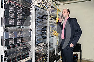 A man in a suit phones a mobile phone in the server room. The specialist works in the datacenter. The chief engineer is next to