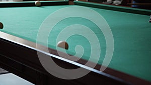 Man in suit plays billiards in dark room on pool table