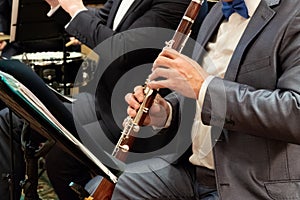 A man in a suit plays the clarinet. Brass band. Musical theme. Male fingers press the keys on the pipe. Close-up