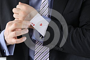 Man in suit puts ace of chirv card into sleeve of his jacket