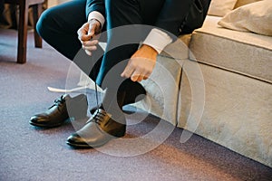 A man in a suit puts shoes on his feet