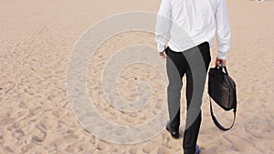 A man in a suit and shoes rides along the beach