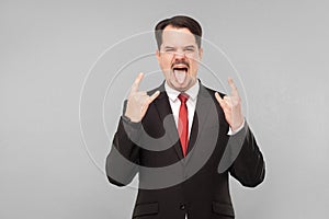 Man in suit showing tongue and rock sign